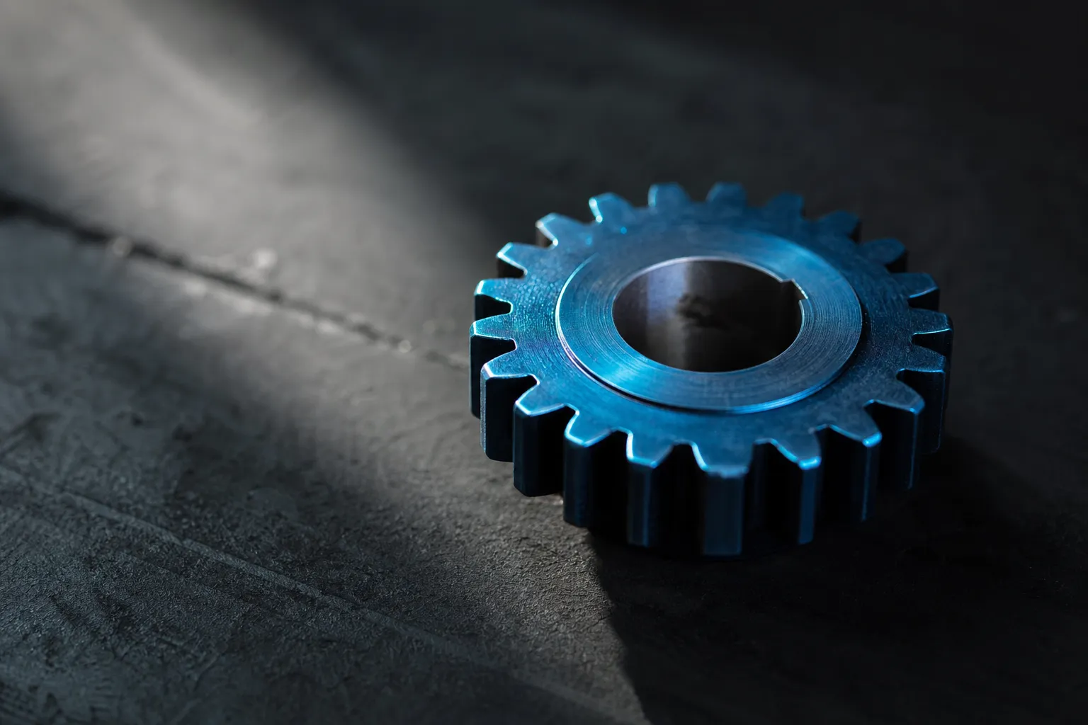 Roue dentée bleue métallique sur surface sombre, symbolisant l’alignement des ressources humaines à la stratégie de l’organisation.
